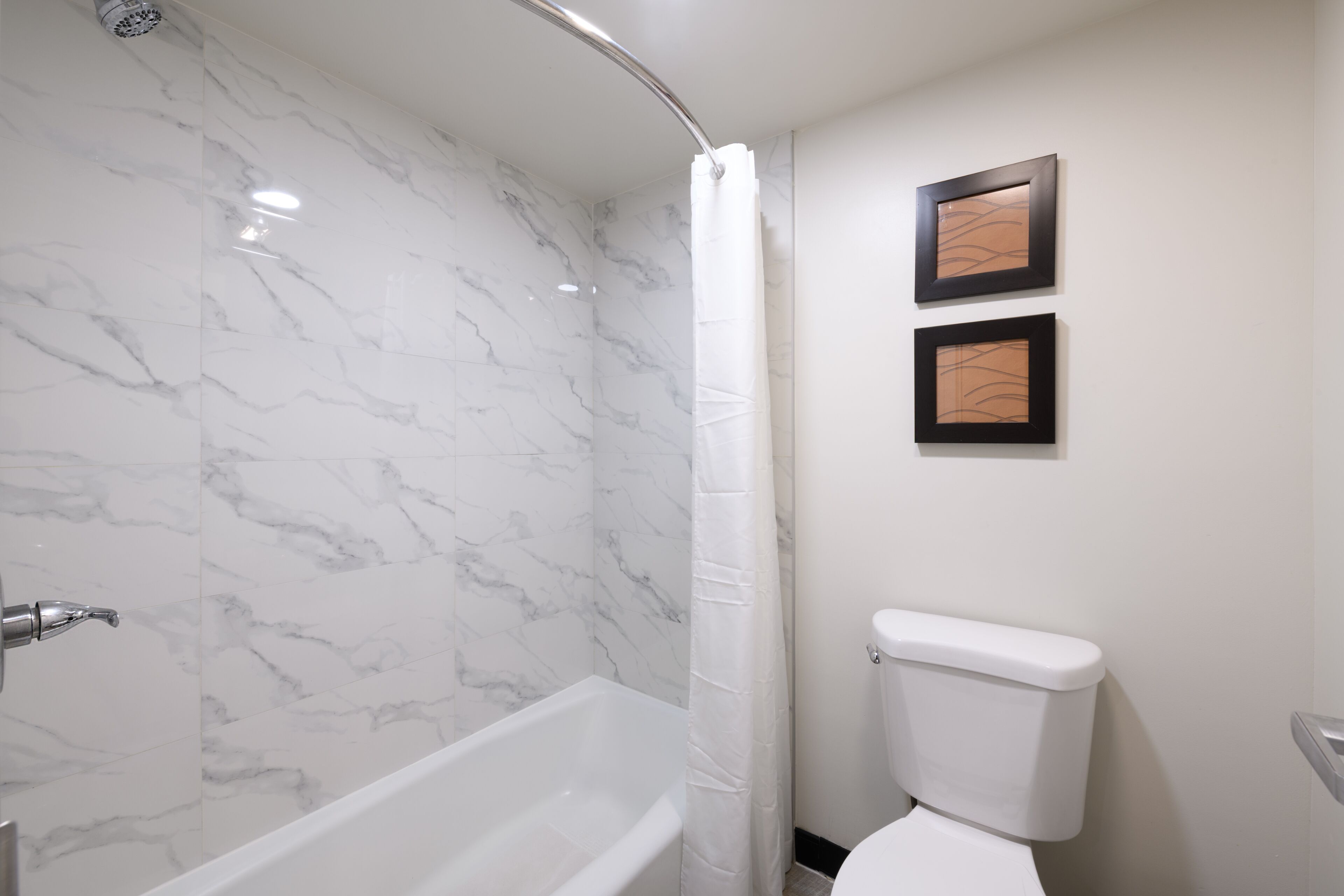 A bathroom with a white bathtub, a shower curtain, and a toilet.