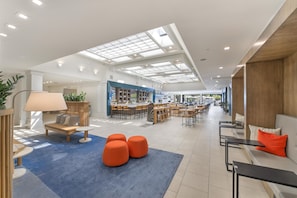 A spacious indoor area with a bar, seating, and a skylight ceiling.