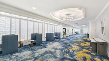 Un hall de hotel con alfombra azul, áreas de descanso y una recepción.