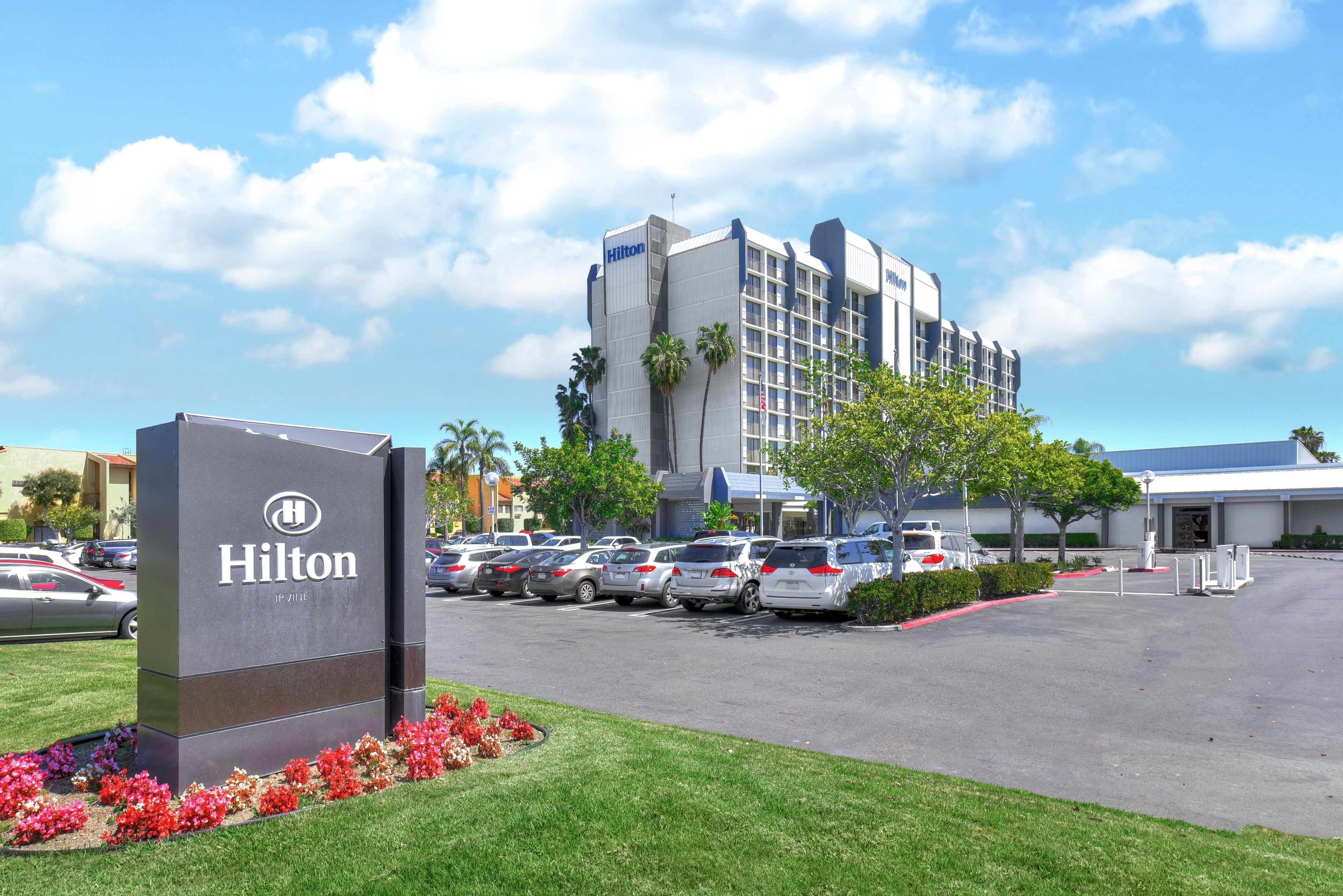 Un hotel Hilton con aparcamiento, un cartel y un edificio de varios pisos con diseño moderno.