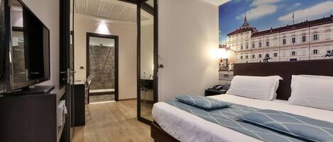 Una habitación de hotel con cama, televisor, escritorio y baño con ducha.