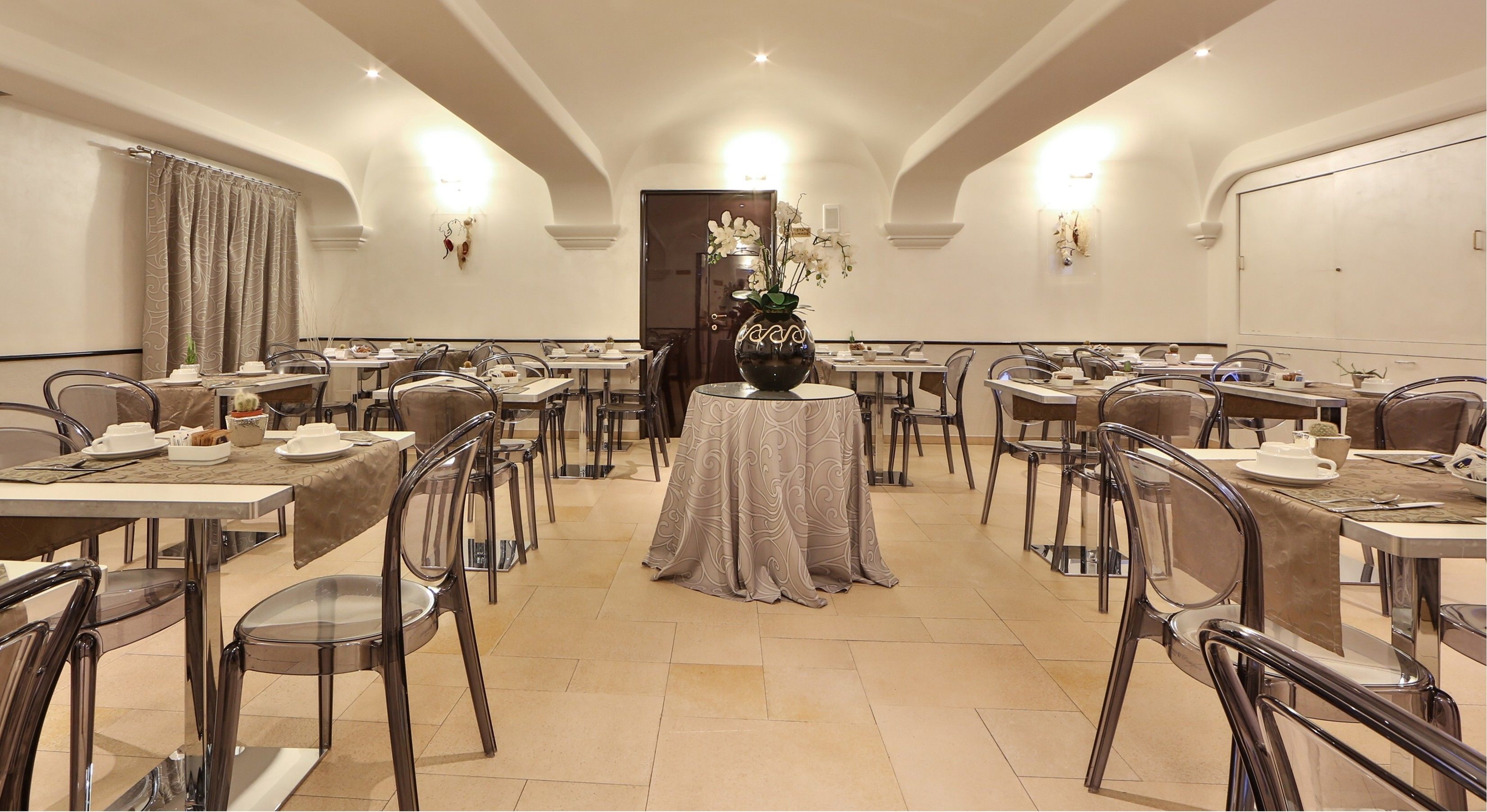A conference room with round tables, chairs, and a central decorative vase.