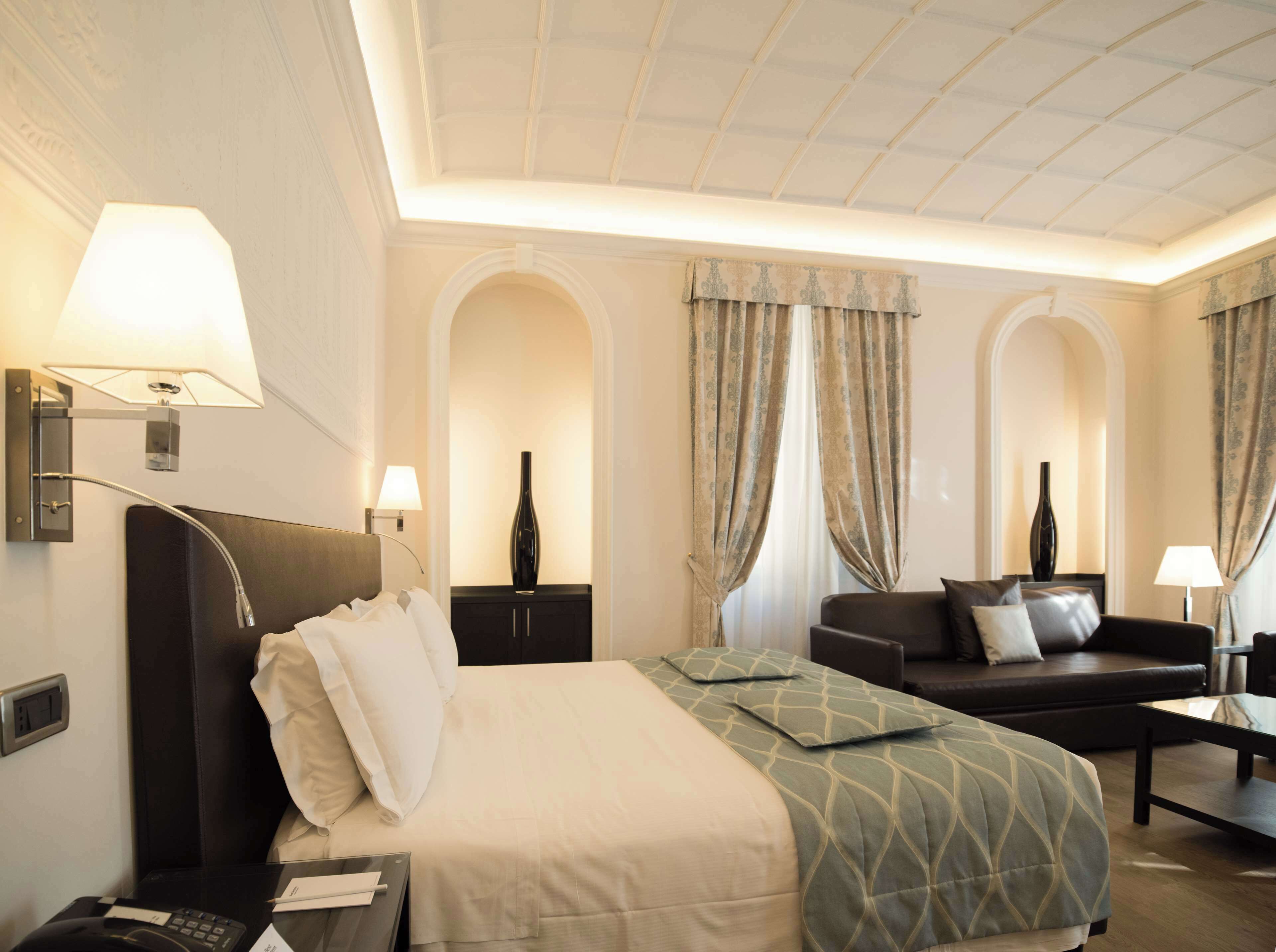 Une chambre d’hôtel avec un lit, un canapé, un bureau et une lampe.