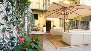 A patio area with a white outdoor sofa, a wooden table, and an umbrella.
