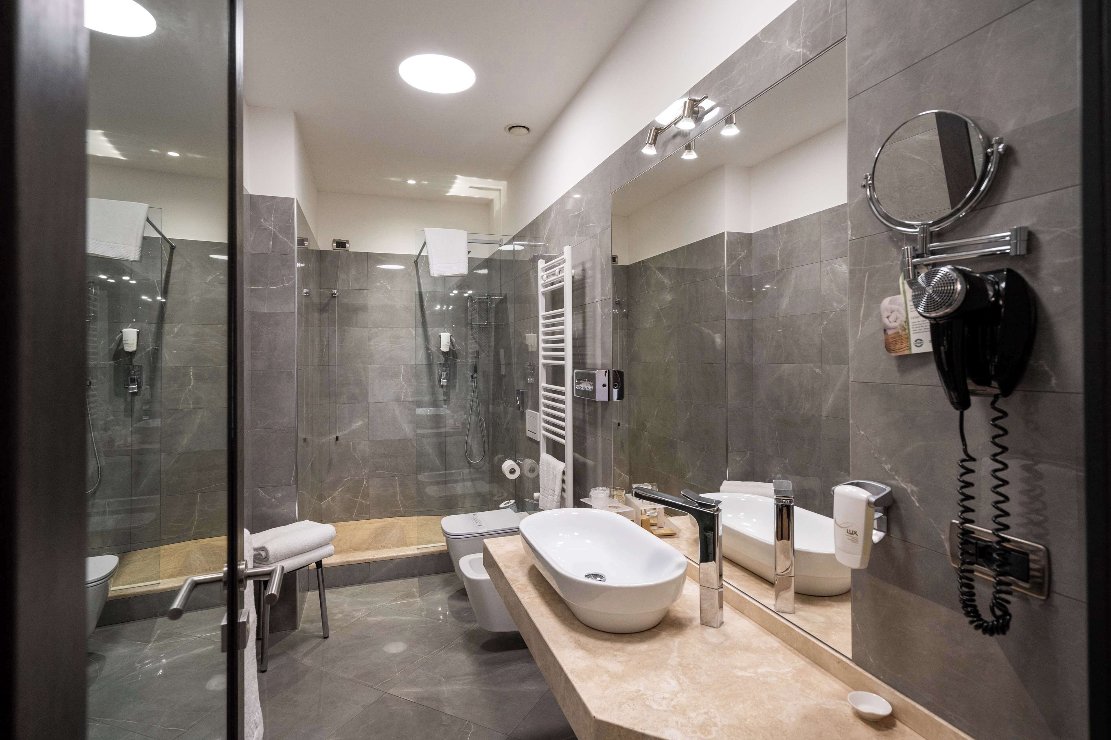 Un baño moderno con ducha acristalada, un lavamanos espacioso con tocador y un secador de pelo incorporado.