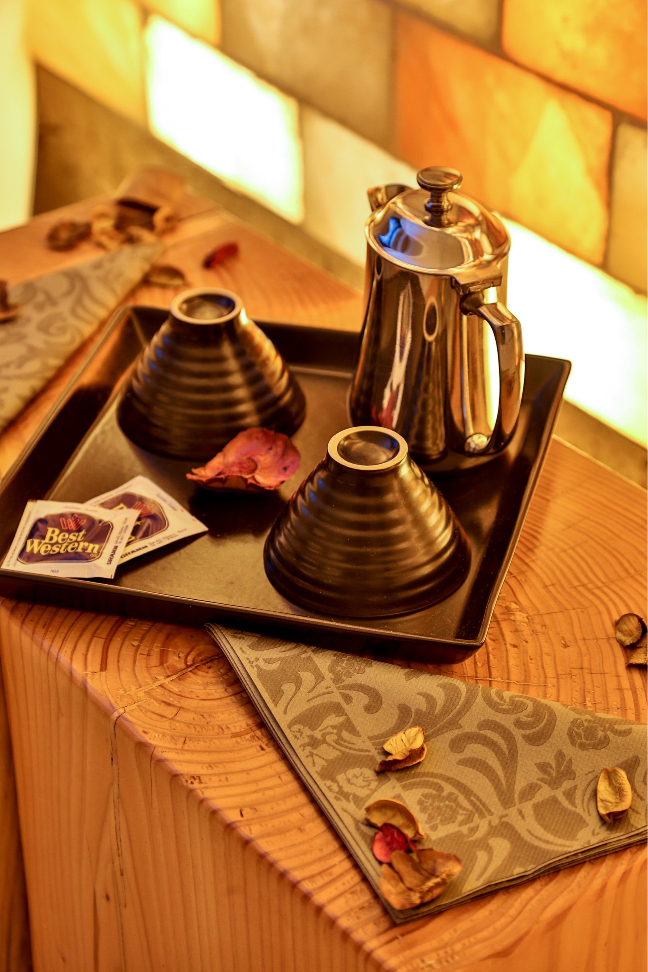 A tray with a coffee maker, two cups, and a Best Western card on a wooden table.