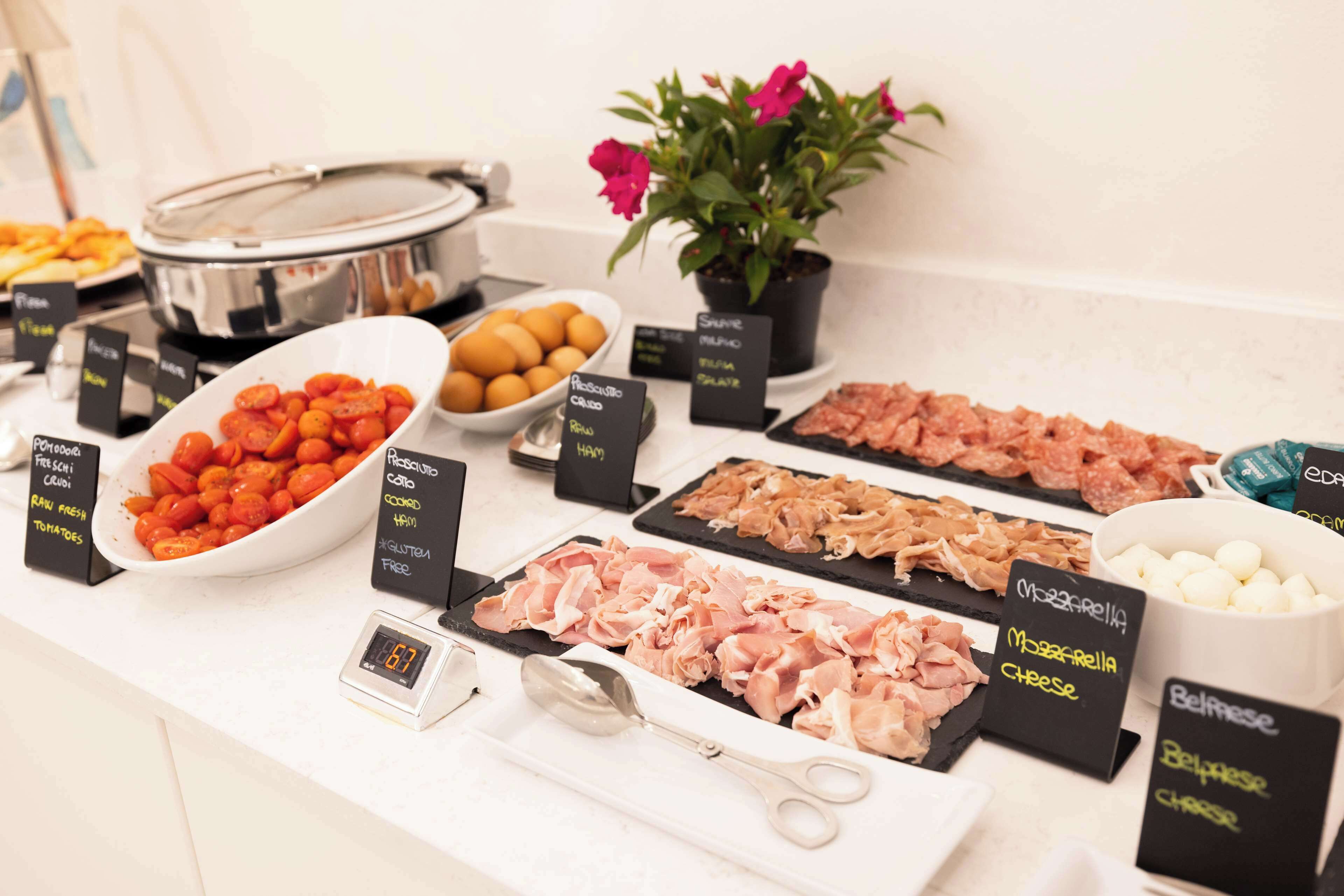 Un buffet con diverse opzioni gastronomiche, tra cui pomodori, uova e vari tipi di carne.