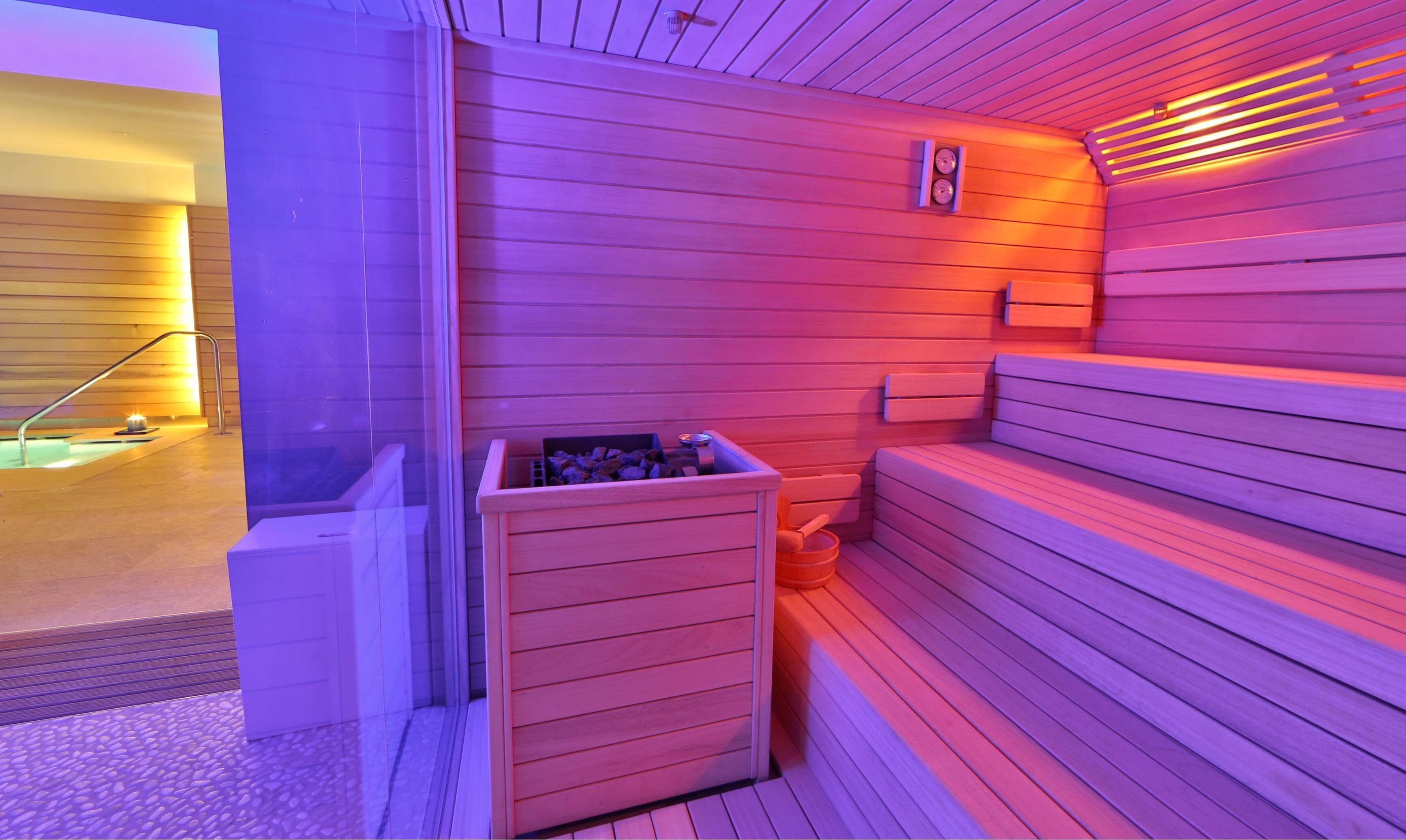 A sauna room with wooden walls, a bench, and a small heater.