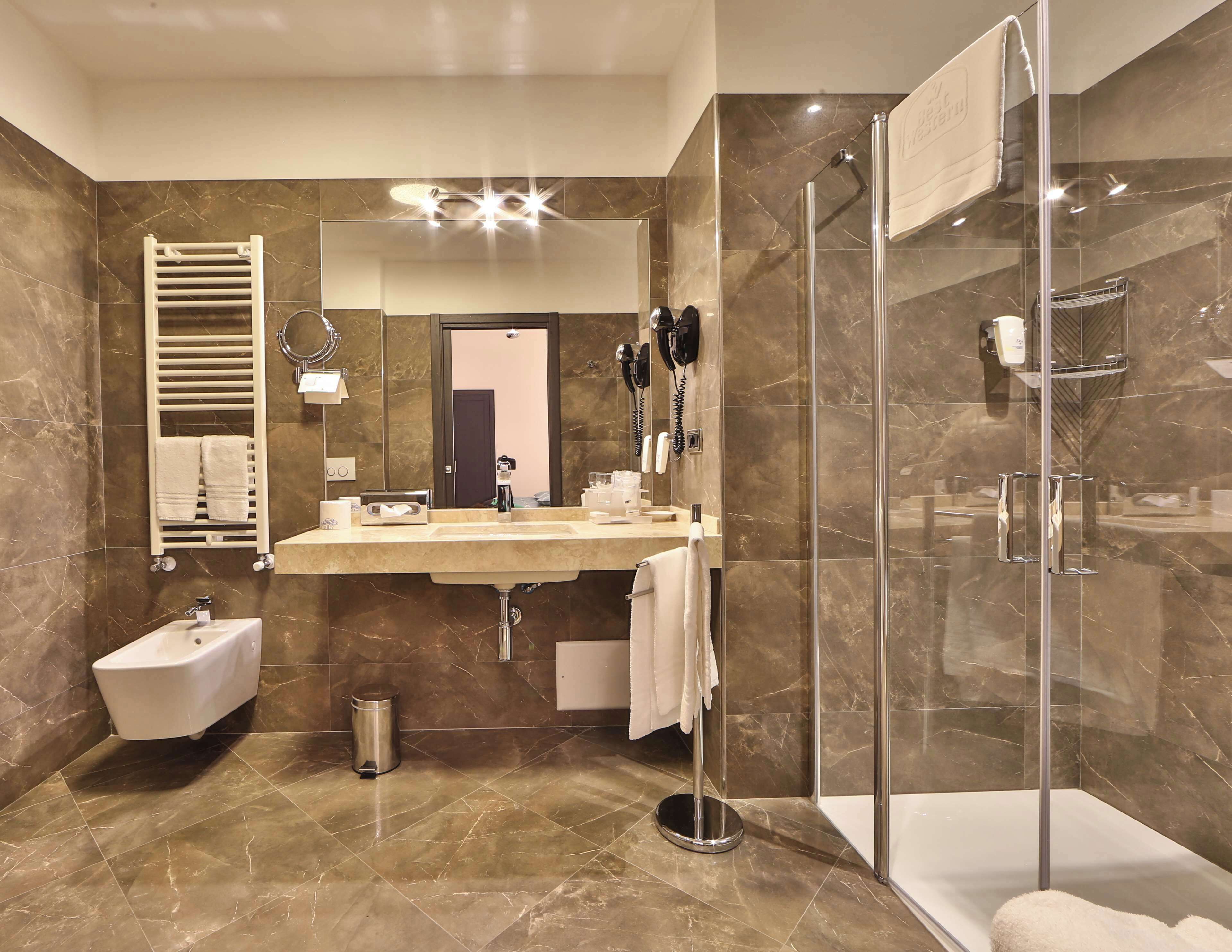 Een moderne badkamer met een marmeren vloer, een inbouwgootsteen, een vrijstaand bad, een douche met glazen wanden en een handdoekhouder.