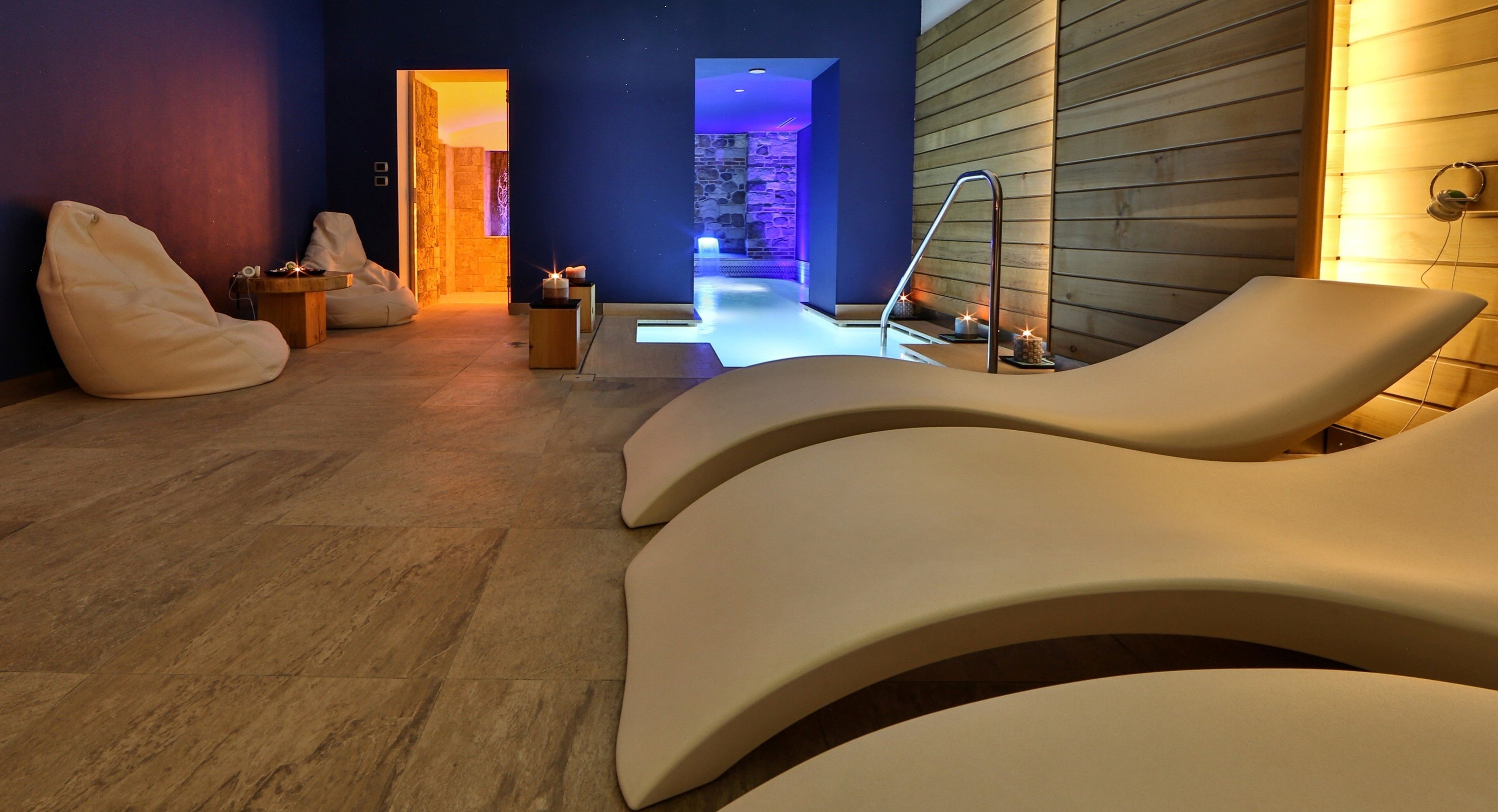 Un'area benessere moderna con poltrone lounge sagomate, una parete in pietra e un pannello di legno.