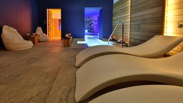 Un'area benessere moderna con poltrone lounge sagomate, una parete in pietra e un pannello di legno.