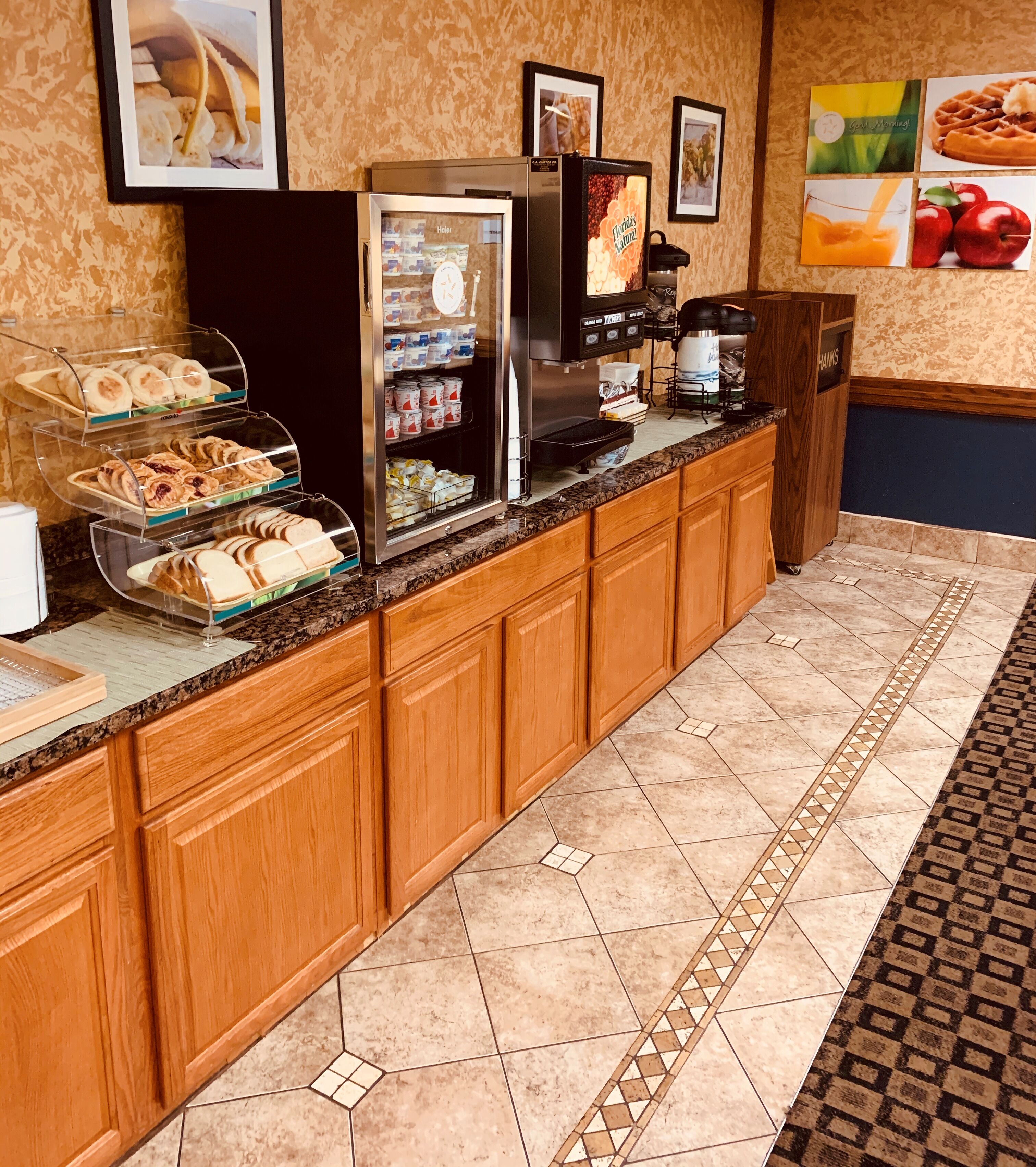 Un bar pour le petit-déjeuner équipé d’une machine à café, d’un réfrigérateur et d’une vitrine réfrigérée où sont présentées des pâtisseries.