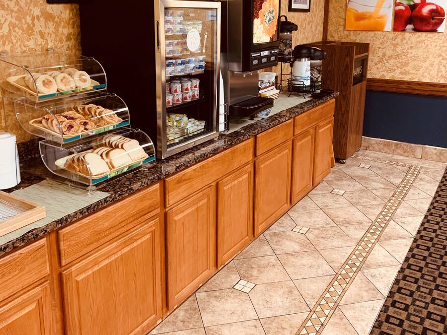 Ein Frühstücksbuffet mit einer Kaffeemaschine, einem Kühlschrank und einer Vitrine mit Gebäck.
