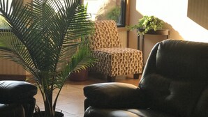A living room with a leather sofa, a patterned armchair, and a potted plant. - Quality Inn Hermitage South (Hermitage)