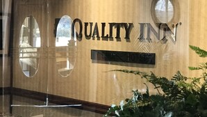 A reception area with a 'QUALITY INN' sign, a reception desk, and a potted plant. - Quality Inn Hermitage South (Hermitage)
