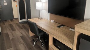 A hotel room with a wooden desk, a flat-screen TV, a lamp, a microwave, and a refrigerator. - Quality Inn Hermitage South (Hermitage)