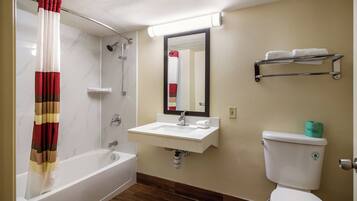 A bathroom with a bathtub, a sink, a toilet, and a mirror.