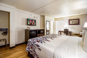 A hotel room with a large bed, a desk, a television, and a chair. - Red Roof Inn Houston East – I-10 (Houston)