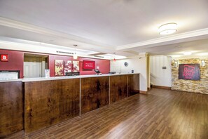 A reception area with a wooden reception desk, a clock, and a sign indicating free Wi-Fi availability. - Red Roof Inn Houston East – I-10 (Houston)