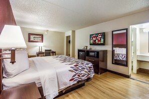 A hotel room with a bed, a desk, a television, and a mirror. - Red Roof Inn Houston East – I-10 (Houston)