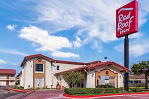 A Red Roof Inn building with a red roof, beige walls, and a clear blue sky. - Red Roof Inn Houston East – I-10 (Houston)