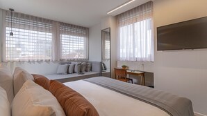 Een moderne hotelkamer met een groot bed, een bureau, een stoel en een televisie aan de muur.