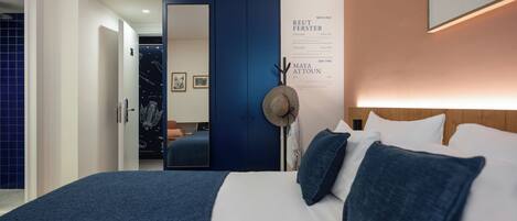 Habitación de hotel con una cama grande, un armario, un espejo y una pared con arte y texto.