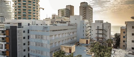 A modern hotel with multiple floors, a rooftop terrace, and a view of the sea.