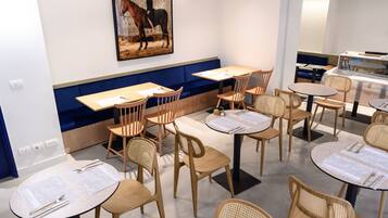 Ein Restaurant mit runden Tischen und Holzstühlen, blau gepolsterten Sitzgelegenheiten und einem Poster über Reiten an der Wand.