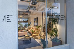 A modern hotel lobby with a seating area, potted plants, and a glass wall. - Artist Hotel - an Atlas Boutique Hotel (Tel Aviv)