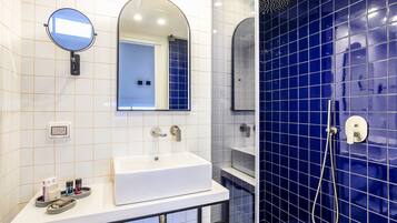 A bathroom with a white sink, mirror, and blue-tiled shower area.