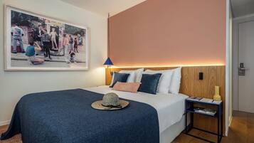Un dormitorio con cama, mesita de noche, lámpara, estante en la pared y un cuadro enmarcado.