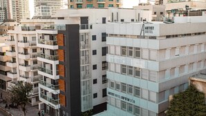 Een modern hotelgebouw met meerdere verdiepingen, balkons en een opvallend bord met de tekst 'Artist Hotel'.