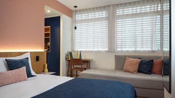 Una habitación de hotel con cama, escritorio, silla y sofá.