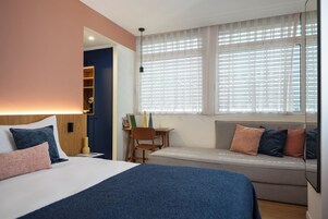 Una habitación de hotel con cama, escritorio, silla y sofá.