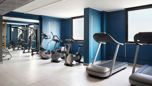 Et moderne fitnesscenter med løbebånd, crosstrainere og styrkeudstyr.