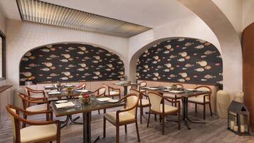 Un restaurante con mesas y sillas altas, techos abovedados y decoraciones de pared con motivos de peces.