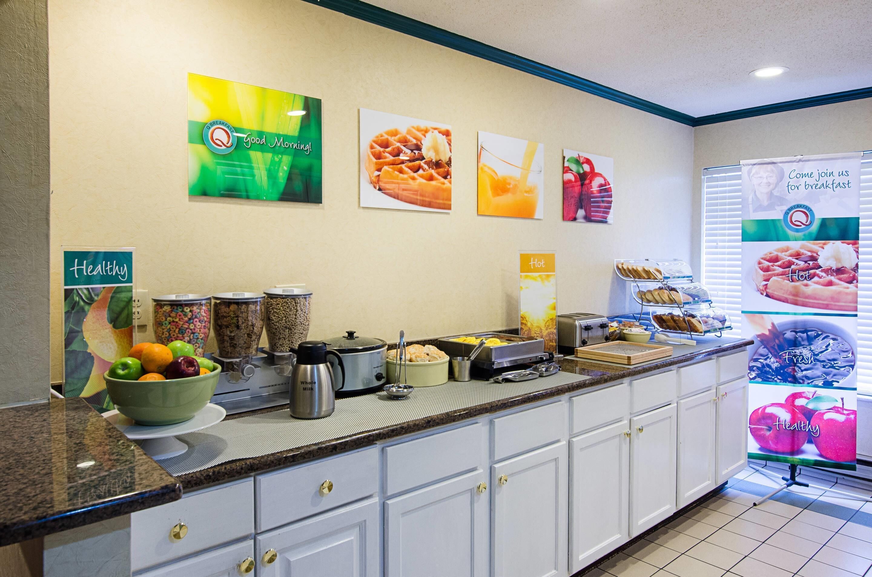 Area colazione a buffet con diverse pietanze e un cartello che promuove una colazione sana.