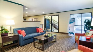 A hotel lobby with a blue sofa, a coffee table, a lamp, and a reception desk.