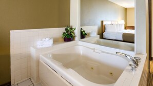 A modern bathroom with a large bathtub, a mirror, and a small potted plant.