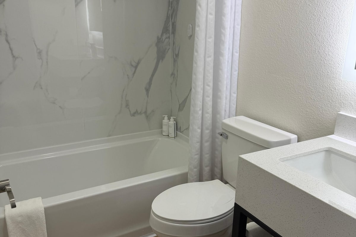 Een bad/douchecombinatie, een haardroger, handdoeken