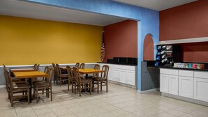 A restaurant with a yellow wall, a red wall, and a blue ceiling. There are wooden tables and chairs, and an American flag is visible.