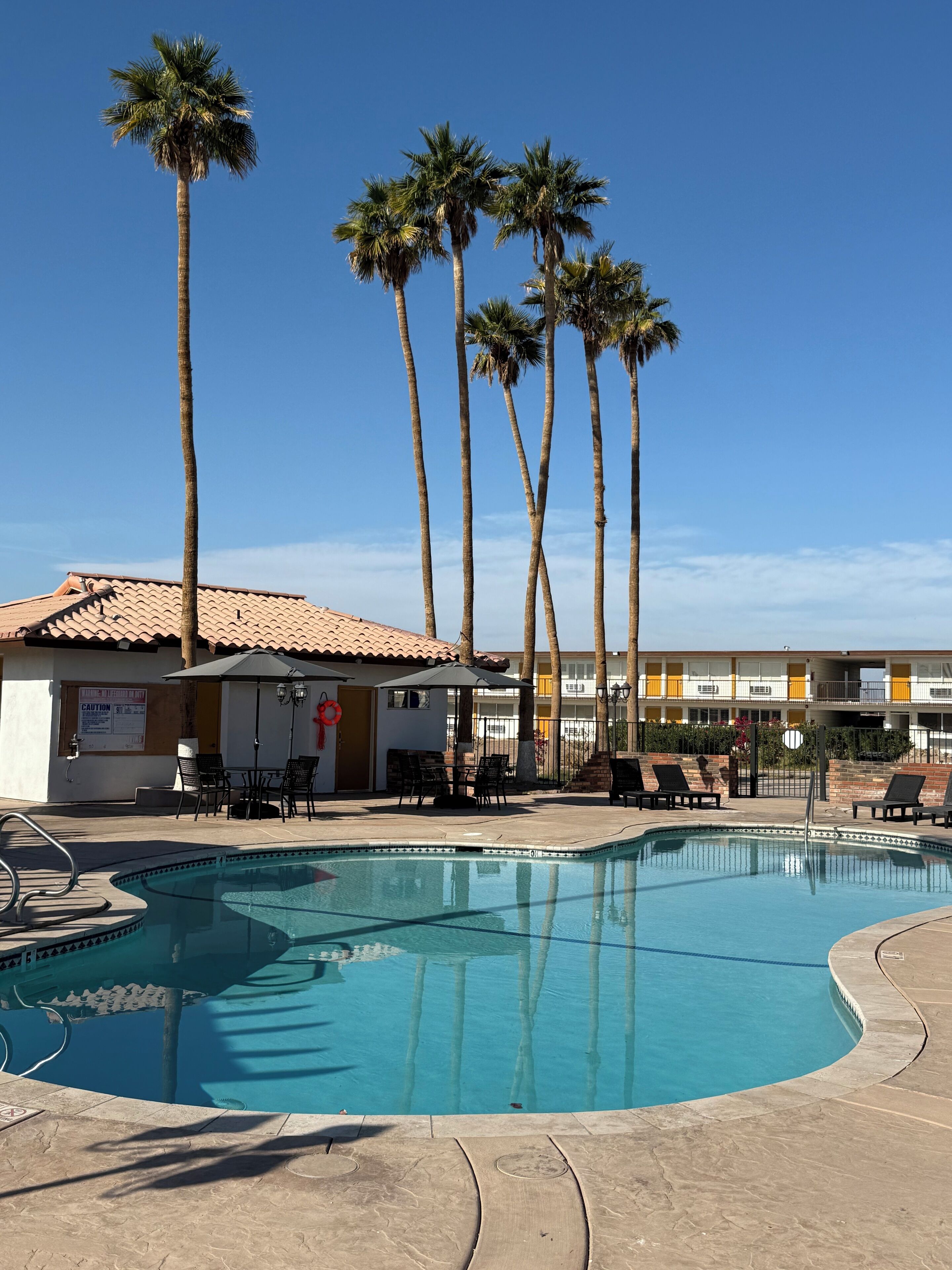 A swimming pool with lounge chairs and a building with a tiled roof.
