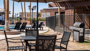 An outdoor patio with tables and chairs, a barbecue grill, and a pool area. - Travelodge by Wyndham Imperial/El Centro (Imperial)