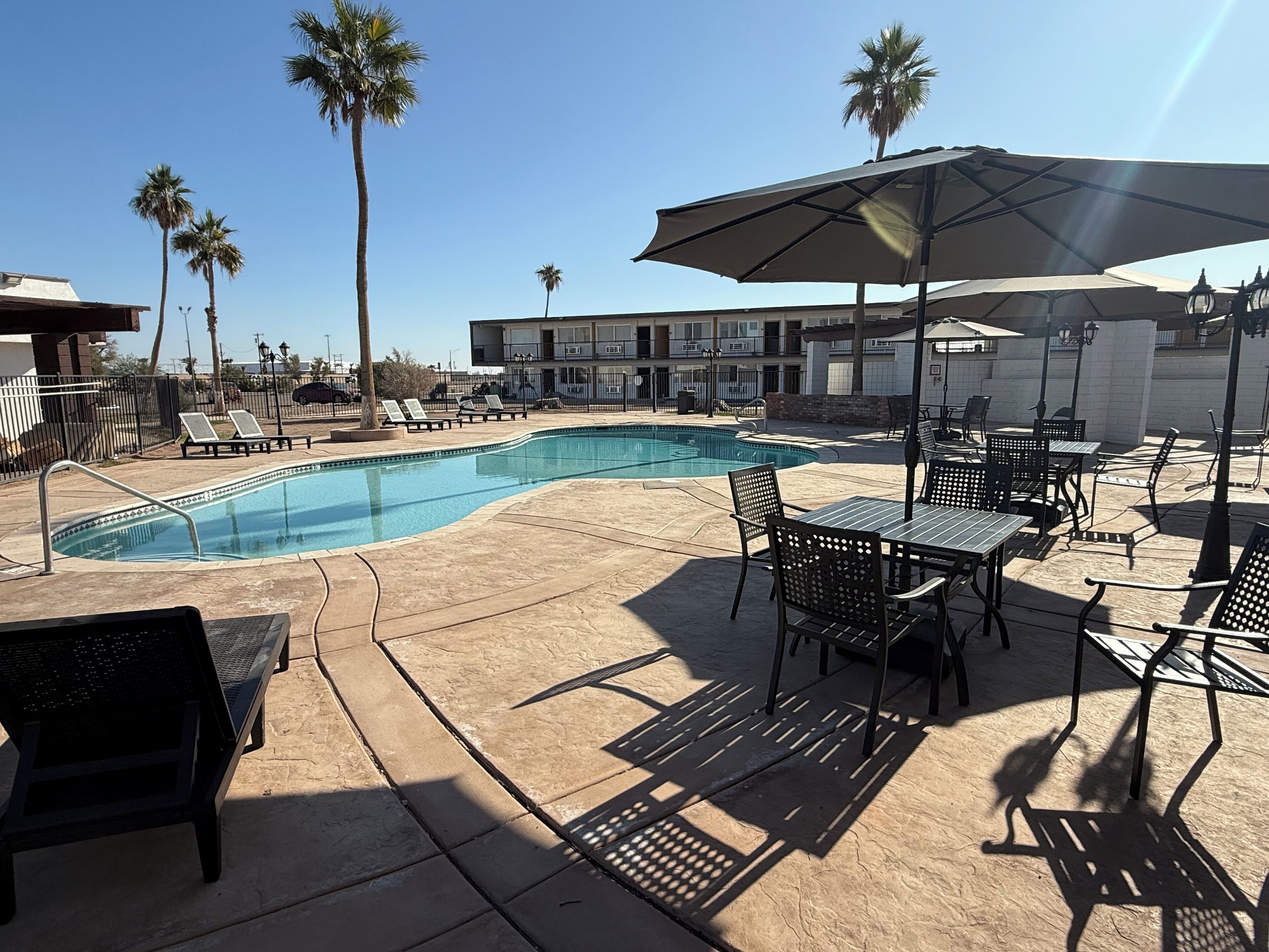 Un área de piscina con sillones, una mesa y sombrillas.
