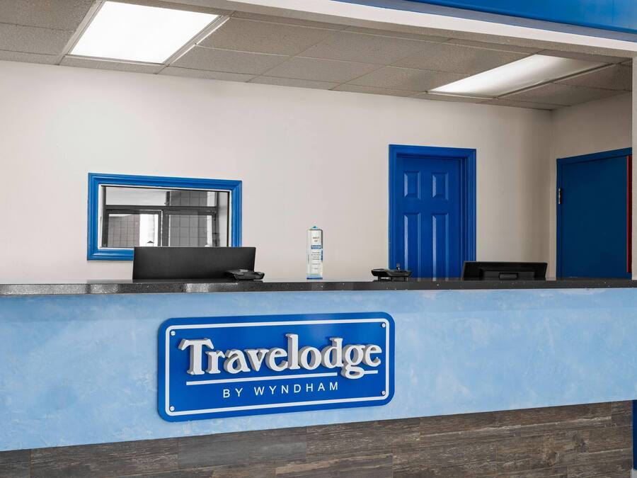 Uma mesa de recepção com uma placa azul que diz 'Travelodge by Wyndham'.