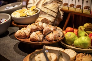 Un bufé con diversos alimentos, incluyendo pan, frutas y limones en rodajas.