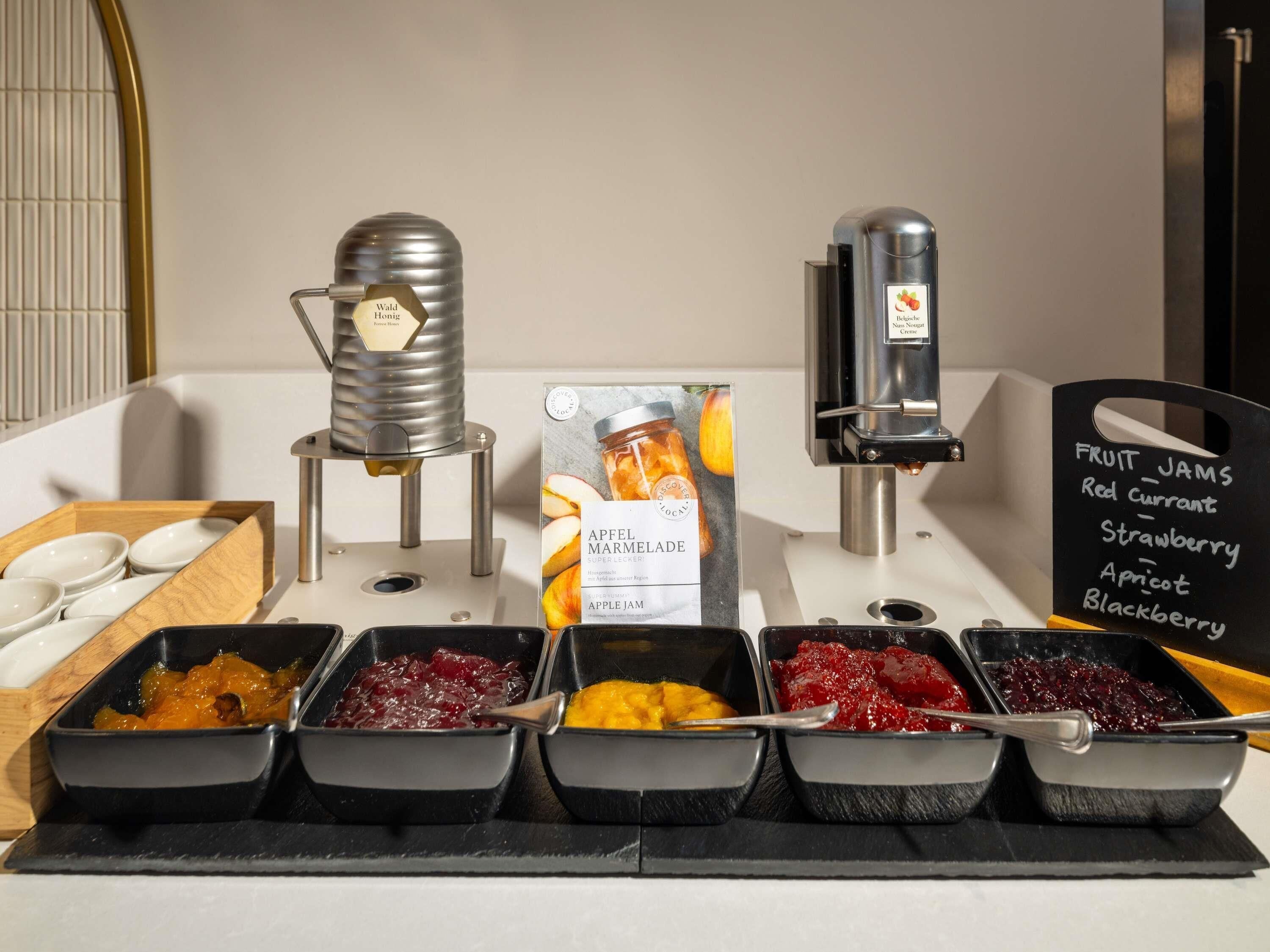 Un bufé de desayuno con diversas mermeladas de frutas y una máquina de café.