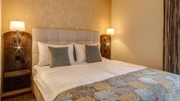 A neatly made bed with a floral bedspread, two bedside lamps, and a wooden nightstand.