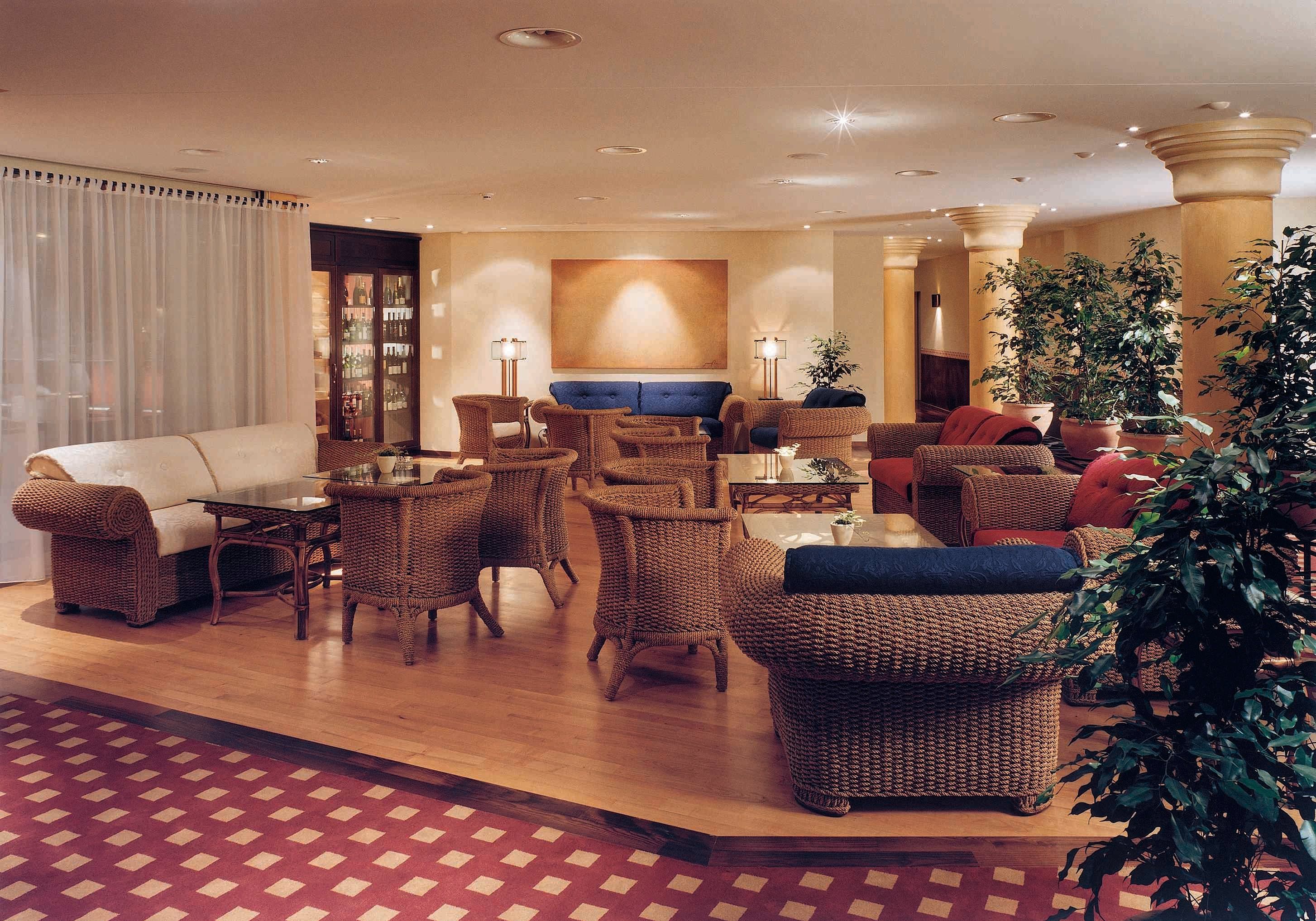 Un hall d’entrée spacieux, doté de meubles en osier, d’un bar et d’une grande plante.